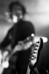 Concert - Zoom sur manche de guitare avec un guitariste flou en arrière-plan