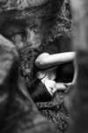 Portrait - Femme allongée entourée de roches avec visage humain