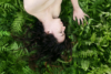 Portrait - Buste de femme allongée sur un tapis de fougères, les cheveux étalés