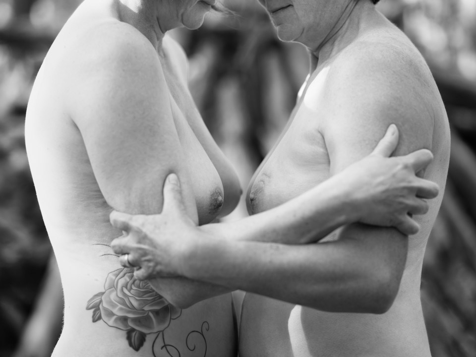 Portrait noir et blanc de 2 femmes nues, face à face, se serrant les bras